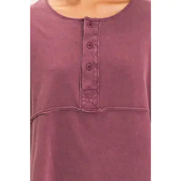 Close-up of a person wearing the Ester Raw Seam Henley in mauve, featuring an oversized fit, round neckline, three-button placket, and chest seam detail.