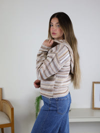 A person wearing a cozy knit striped Romy Hooded Cardigan Sweater and blue jeans.