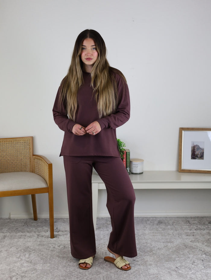 A person wearing a matching dark plum long-sleeved top and Adaline Wide Leg Sweatpants.