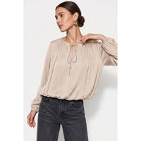 Wine-colored Naked Zebra - Long Sleeve Draped Bubble Hem Blouse: Wine / L with a gathered neckline and tie detail, tucked into grey jeans.