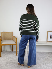 Back view of a person wearing a dark green and white oversized Noa Striped Sweater in cotton knit paired with blue wide-leg jeans.