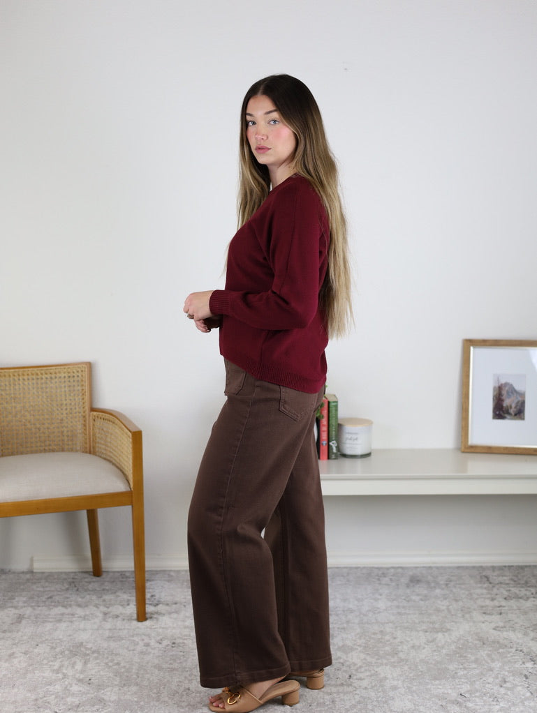 A person wearing an Eli Front Seam Sweater in maroon with a round neck and brown wide-leg pants.