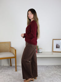 A person wearing an Eli Front Seam Sweater in maroon with a round neck and brown wide-leg pants.