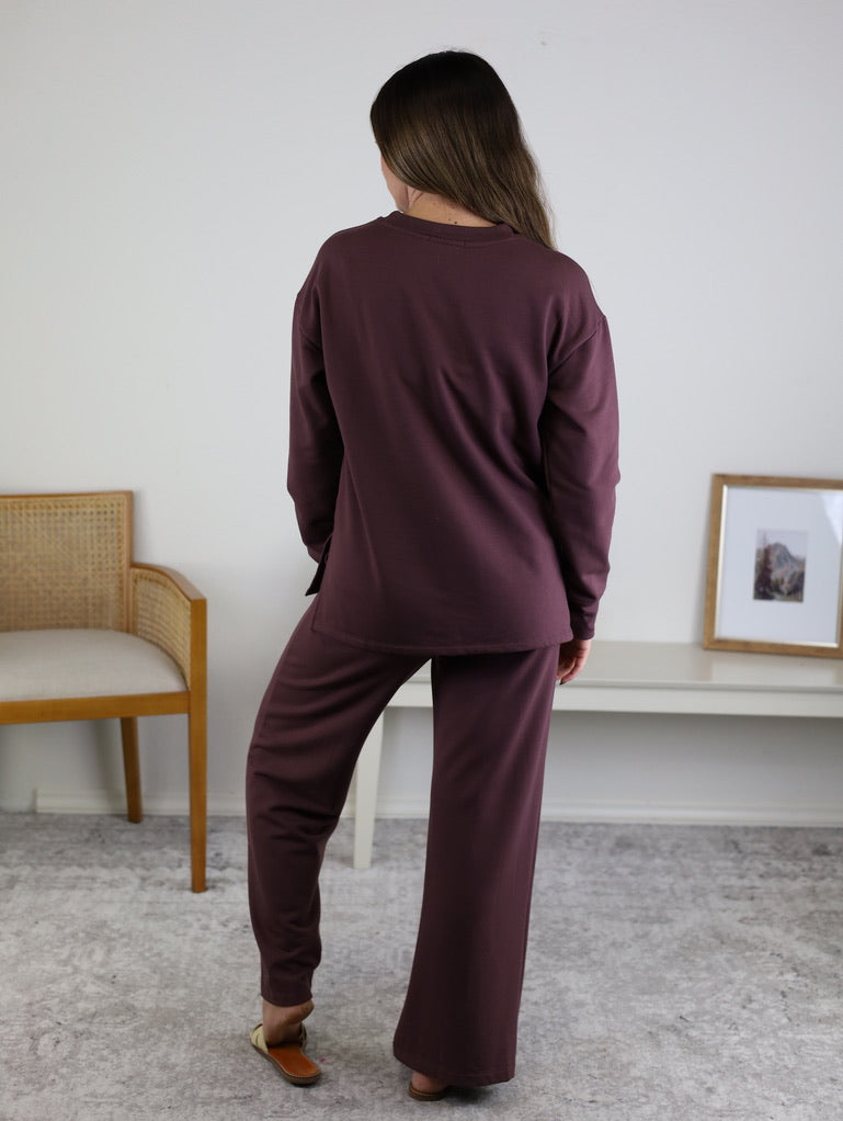 A person seen from behind wearing a matching dark purple long-sleeved top and Adaline Wide Leg Sweatpants.