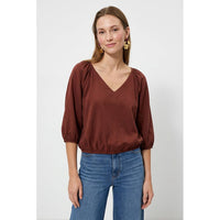 Naked Zebra - Elastic Puff Sleeve V-neck Blouse: Burgundy / L, a burgundy V-neck puff sleeve blouse with an elasticized waist, worn with blue jeans.