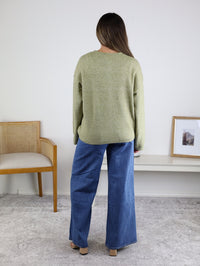 A person viewed from behind wears an Olive Oversized Cardigan and wide-leg blue jeans.