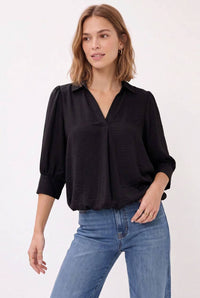 A woman wearing a Naked Zebra - Half Sleeve Hi-lo Bubble Hem Blouse in wine, paired with blue jeans.