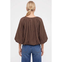 Back view of a Naked Zebra - Crinkle Texture Bubble Hem Button Up Blouse: Black / L, featuring a crinkle texture, gathered shoulders, and a bubble hem tucked into blue jeans.