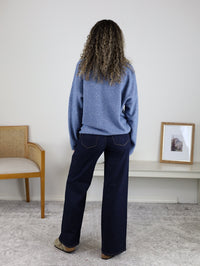 A person seen from behind, wearing a long-sleeved, lightweight blue Davis Lightweight Cardigan and dark blue wide-leg jeans.