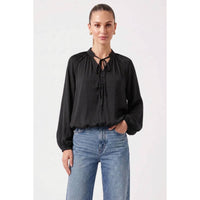 A wine-colored Naked Zebra - Billowy Tie Neck Long Sleeve Blouse with a button-front detail and gathered cuffs, worn with blue jeans.