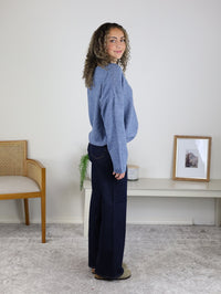A person in profile wearing a soft knit Davis Lightweight Cardigan and dark blue wide-leg jeans.