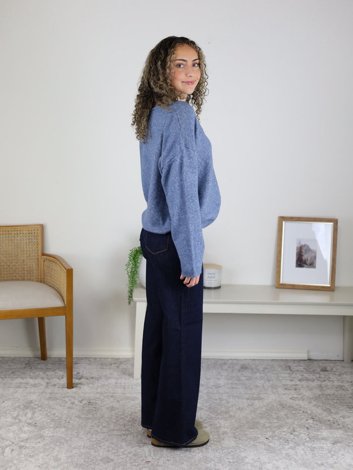 A person in profile wearing a soft knit Davis Lightweight Cardigan and dark blue wide-leg jeans.