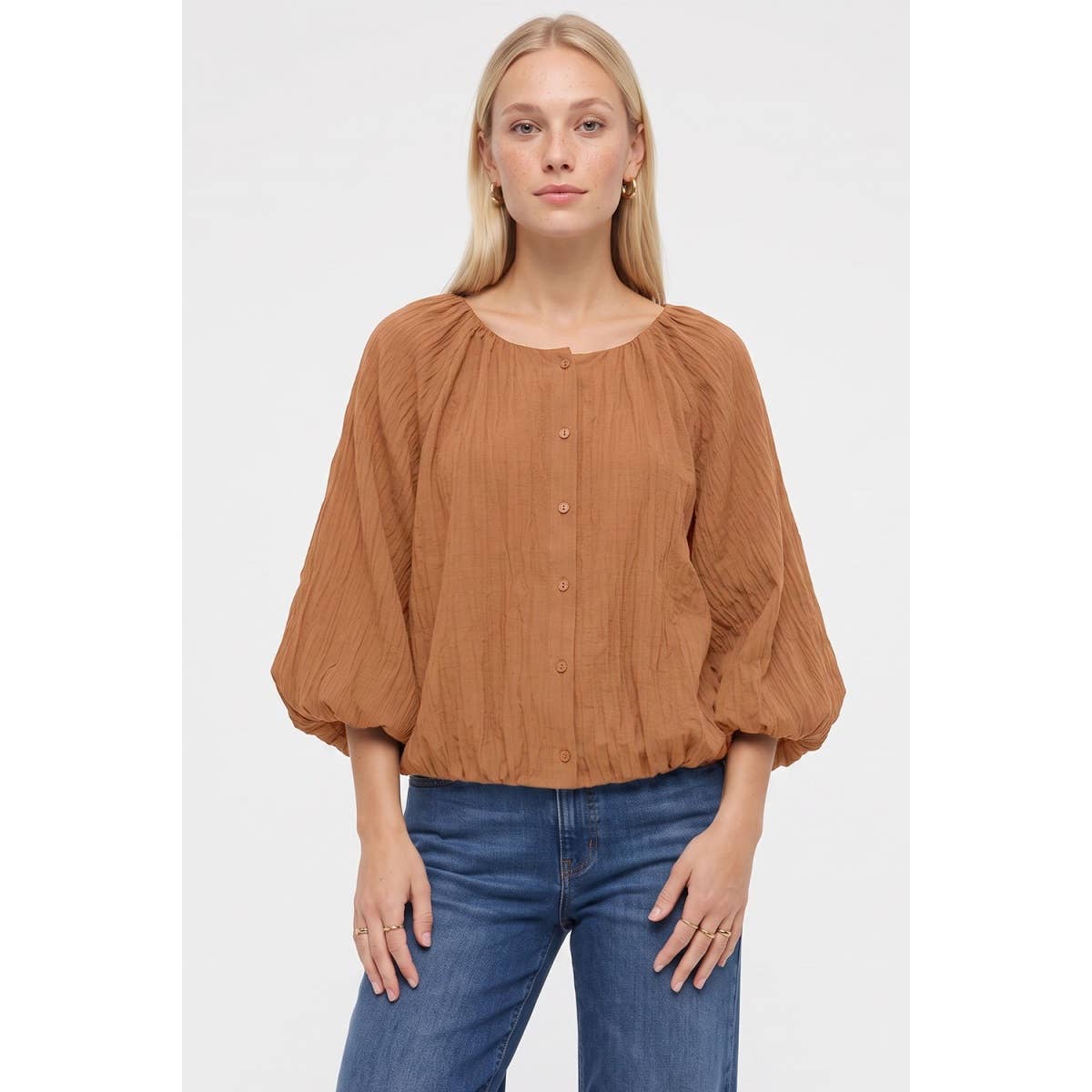A woman wears a black Naked Zebra - Crinkle Texture Bubble Hem Button Up Blouse with long, full sleeves and a gathered bubble hem, paired with blue jeans.