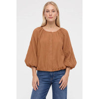 A woman wears a black Naked Zebra - Crinkle Texture Bubble Hem Button Up Blouse with long, full sleeves and a gathered bubble hem, paired with blue jeans.