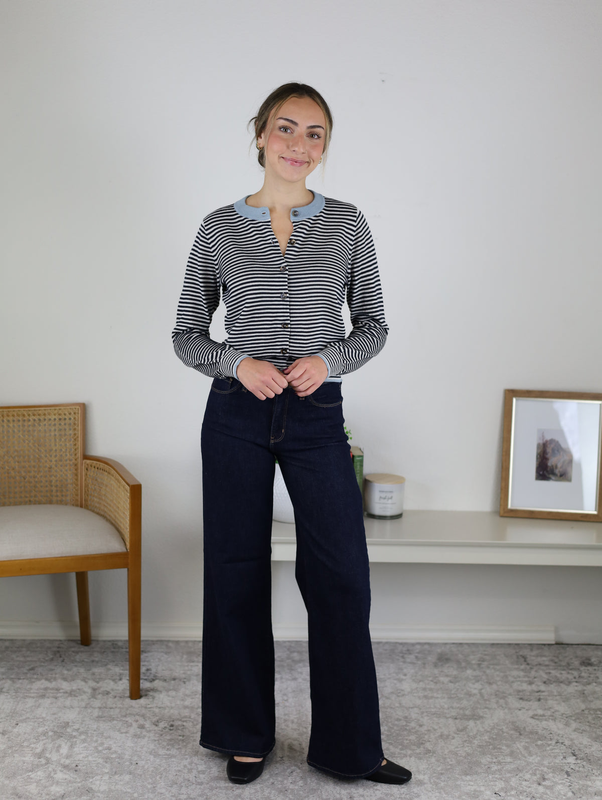A woman wearing a Vera Striped Cardigan in a navy and white knit with light blue trim and dark wash wide-leg jeans, perfect for fall layering.