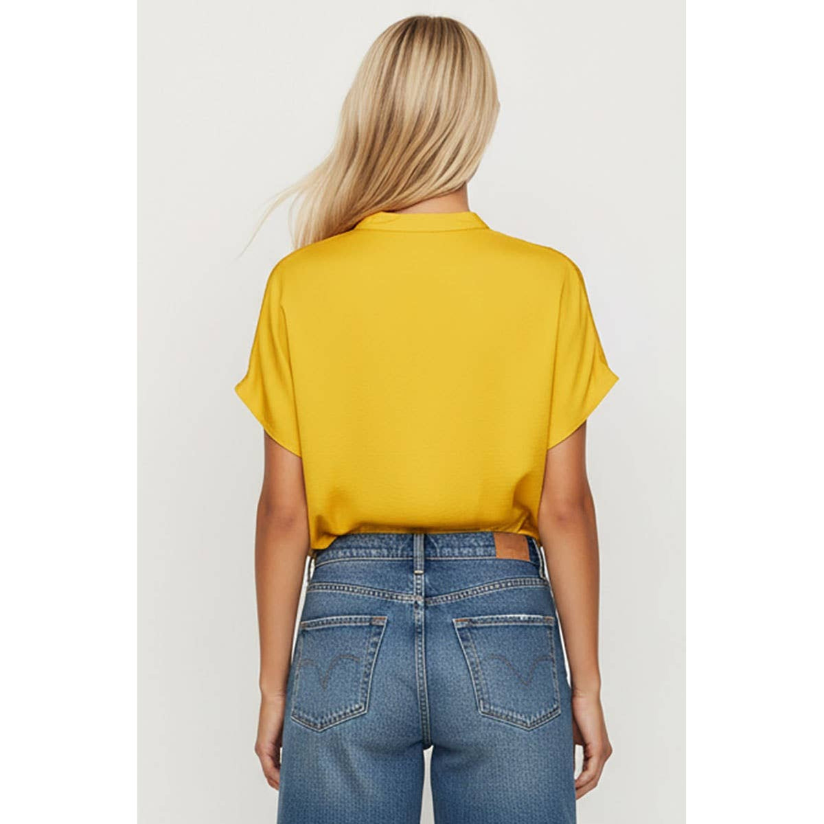 Back view of a person wearing a Naked Zebra - Drop Shoulder Regular Blouse: Chocolate / L in mustard yellow with blue jeans.