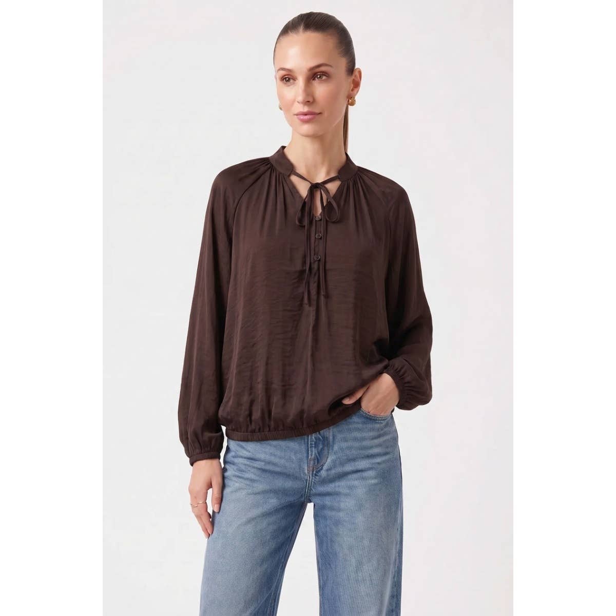 Woman wearing a wine Naked Zebra - Billowy Tie Neck Long Sleeve Blouse with a billowy fit, long sleeves, and an elasticized hem, paired with blue jeans.