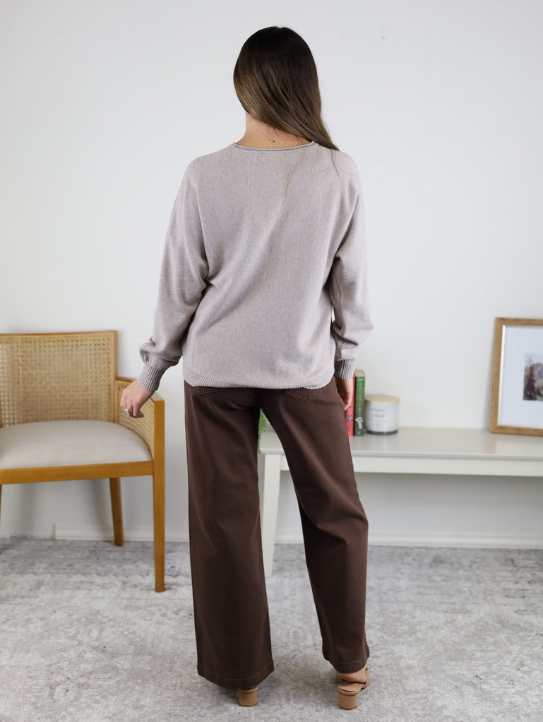A person seen from behind wearing a light beige Eli Front Seam Sweater and dark brown wide-leg trousers.