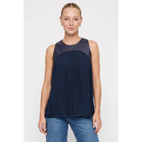 A person wears a wine-colored Naked Zebra - Vegan Leather Yoke Satin Tank, featuring a smooth faux leather yoke and a gathered satin bodice.