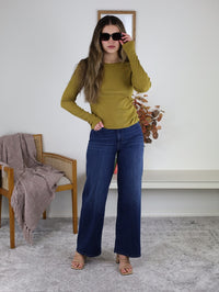 A woman wearing a long-sleeved Dijon yellow ribbed Dee Ribbed Round Neck Tee, dark wash wide-leg jeans, and sunglasses.