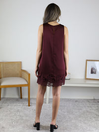 Back view of a sleeveless, burgundy Birch Satin Lace hem Mini Dress with a lace hemline, paired with black heeled mules.