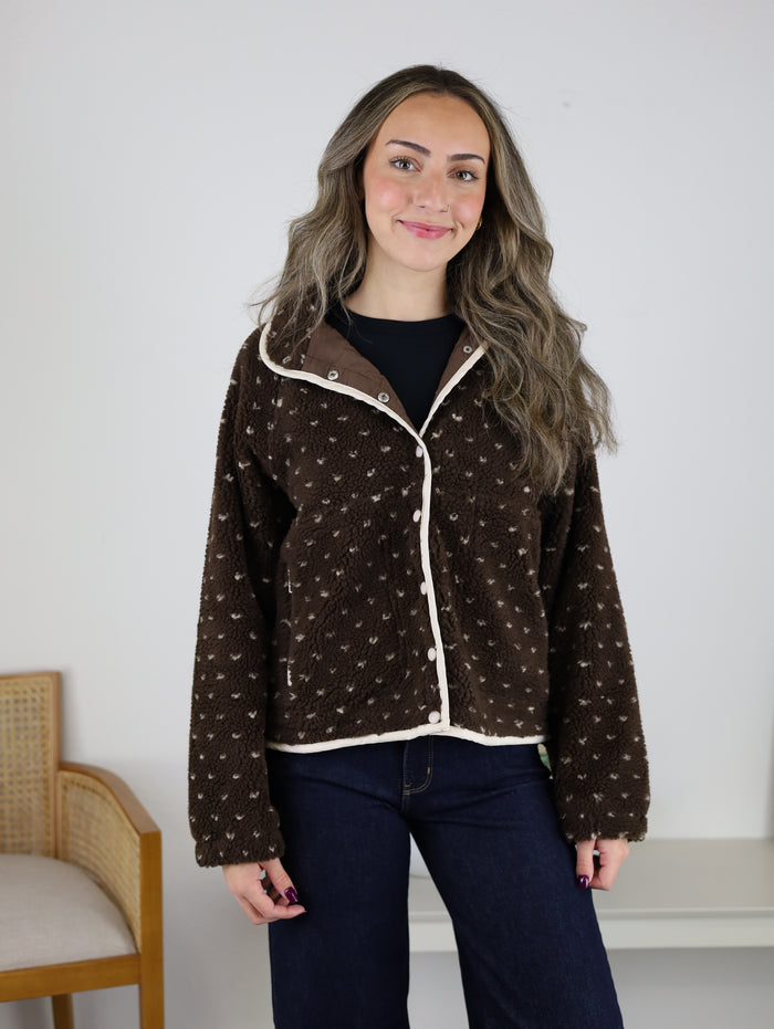A person wearing a Reba Fleece Puffer Jacket in a brown, high-pile fleece with a snap-button front, cream-colored trim, and a patterned design.