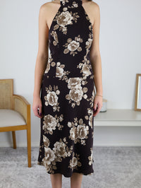 A person wearing the brown floral Nash Halter Neck Midi Dress, perfect as a fall wedding guest outfit.
