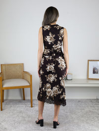 A woman stands with her back to the camera wearing a brown floral Dawson V-Neck Sleeveless Top and matching midi skirt with a cream floral print and a black lace hem.