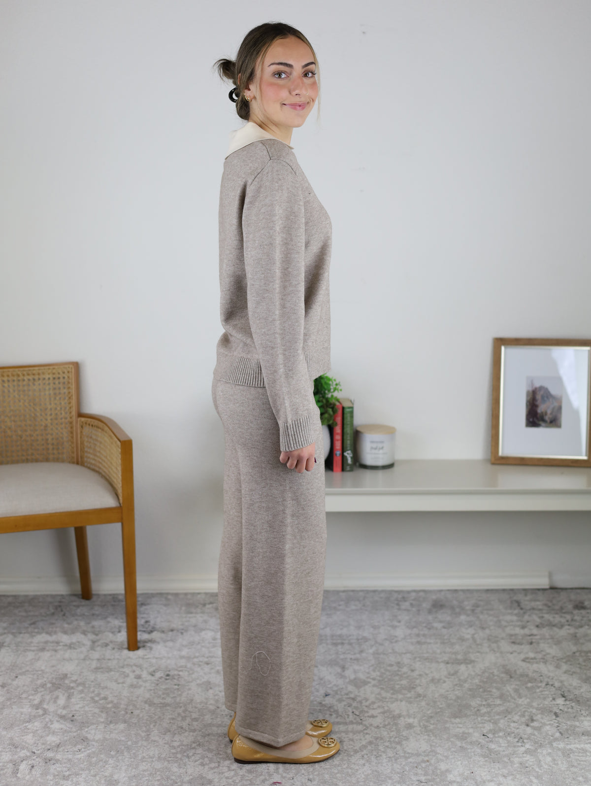 A woman wearing a cozy, matching tan Rebecca Sweater/Pant Set in a knit material with wide-leg pants.
