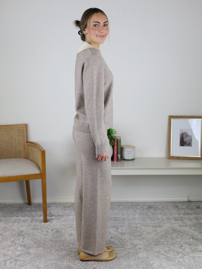 A woman wearing a cozy, matching tan Rebecca Sweater/Pant Set in a knit material with wide-leg pants.