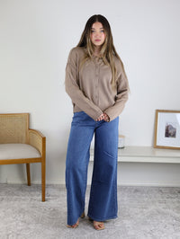 A tan Jude Raw Edge Cardigan worn with wide-leg blue jeans and tan sandals.