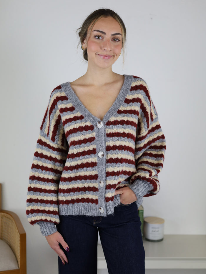 The Grayson Relaxed Stripe V-Neck Button Cardigan is a cozy, relaxed-fit sweater featuring horizontal stripes in red, cream, and grey with a button-front closure.