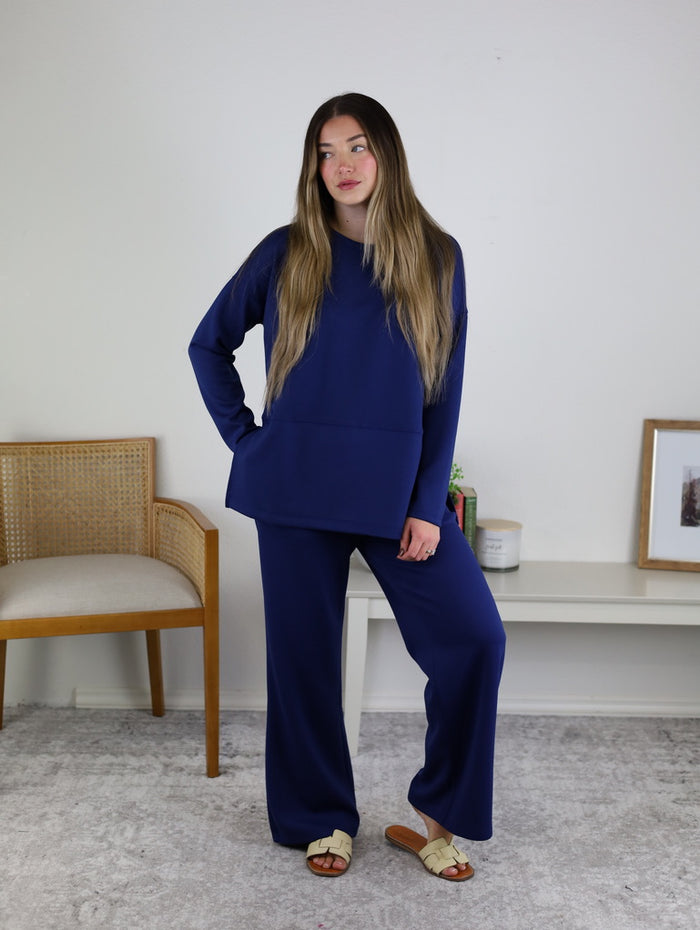A person wearing a navy blue Arbor Lounge Set featuring a long-sleeved top and matching wide-leg pants.
