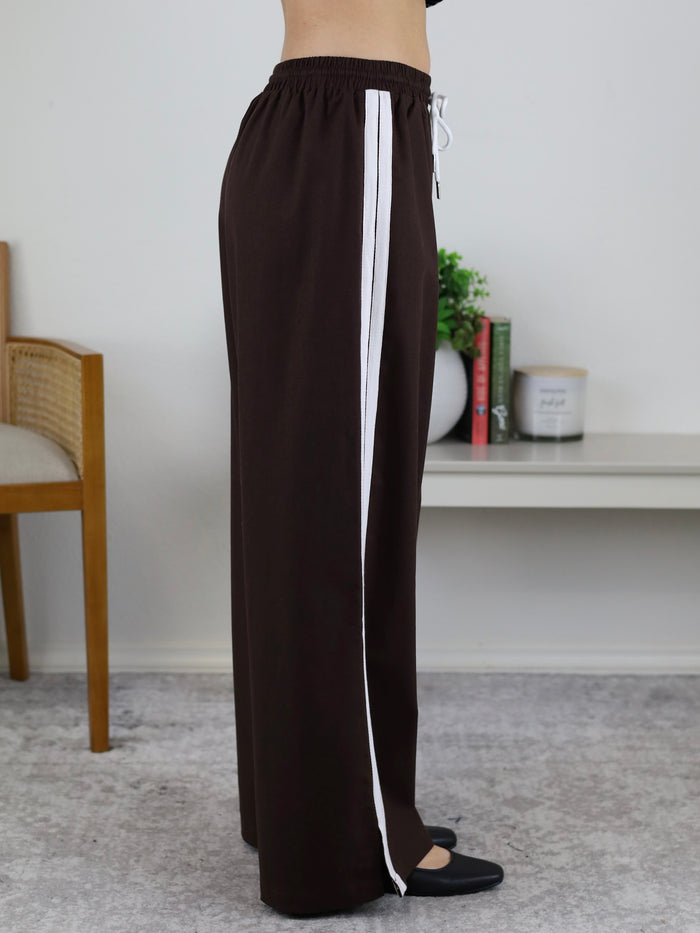 Profile view of Urban Wide Leg Side Stripe Linen Track Pant in dark brown with a white side stripe and a drawstring waist.