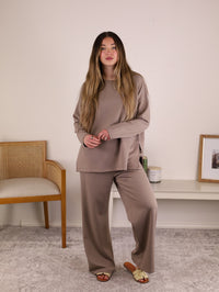 A person wears the taupe Arbor Lounge Set, a long-sleeved, crew-neck sweater and matching wide-leg trousers in scuba knit.
