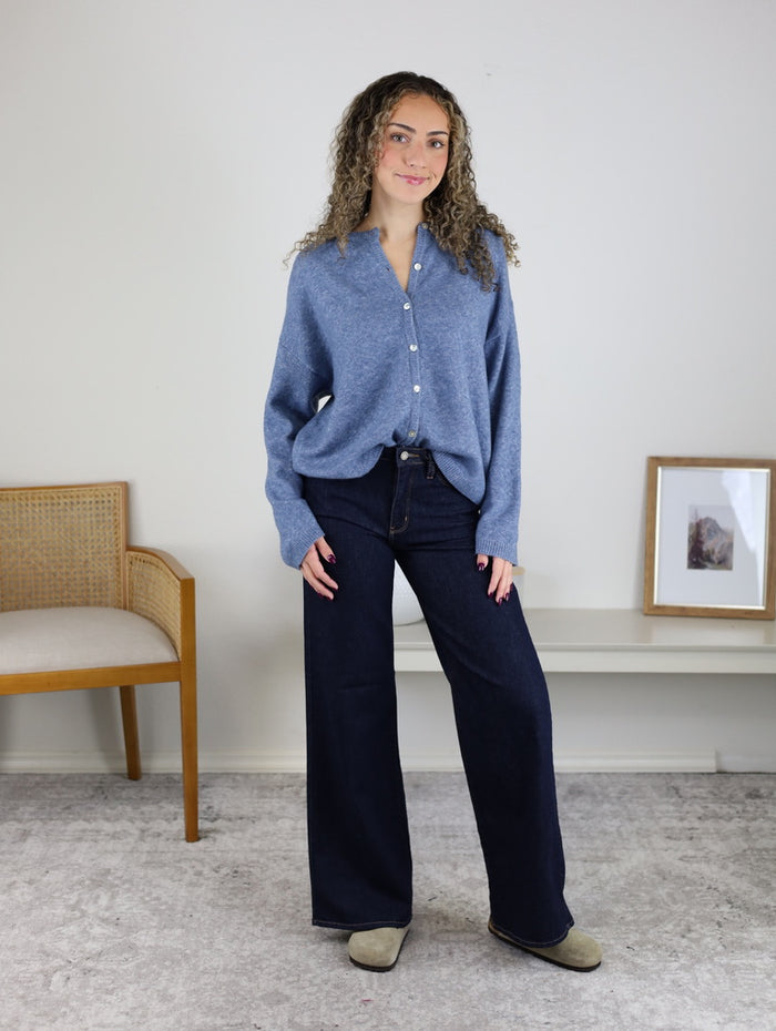 A woman wearing a soft knit Davis Lightweight Cardigan and wide-leg dark wash jeans.