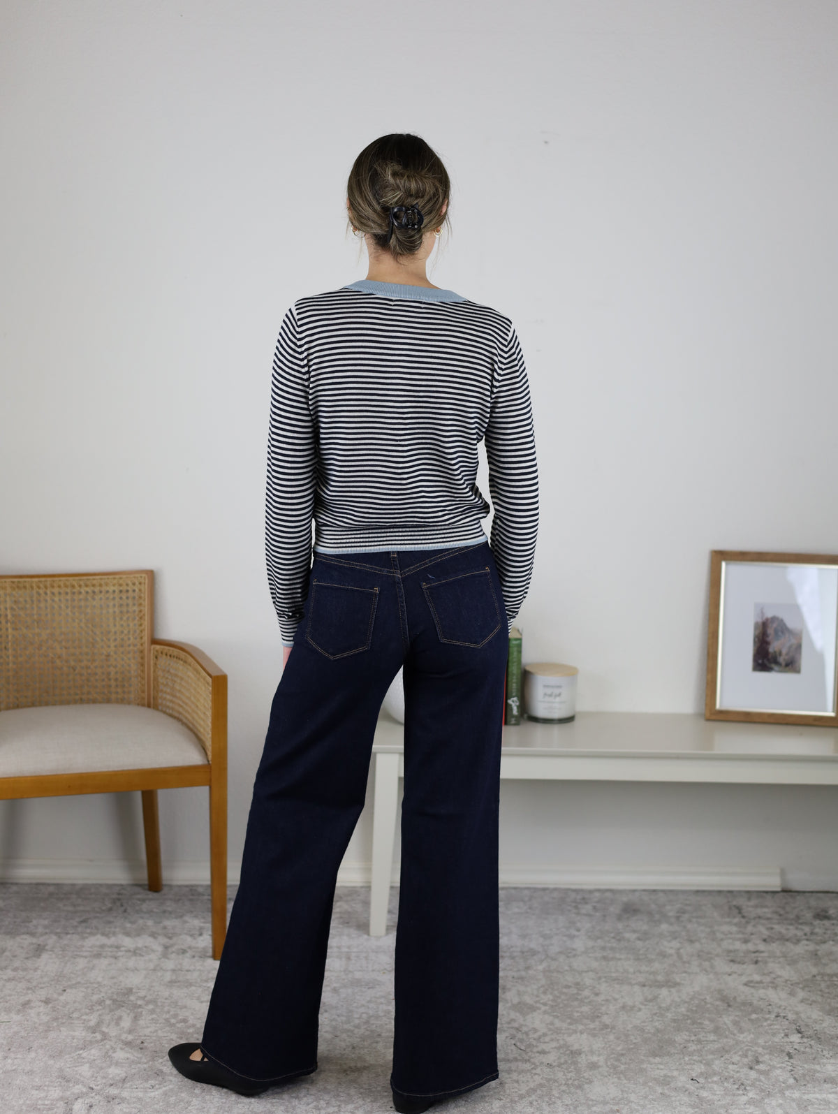 Back view of a person wearing a black and white striped Vera Striped Cardigan for fall layering, styled with a light blue collar and dark blue wide-leg jeans.