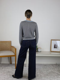 Back view of a person wearing a black and white striped Vera Striped Cardigan for fall layering, styled with a light blue collar and dark blue wide-leg jeans.
