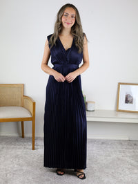 A woman wearing a navy blue Petal Pleated Satin V Neck Maxi Dress with a sleeveless, pleated design and a V-neckline.
