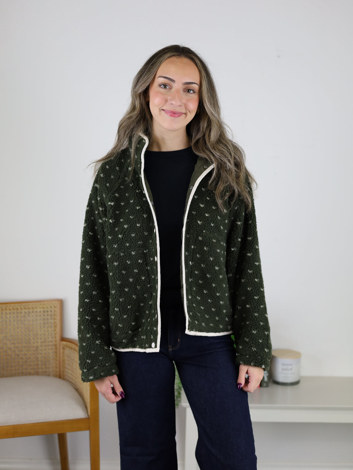 A woman wears an olive green, high-pile Reba Fleece Puffer Jacket with a white-trimmed collar and button-up front.