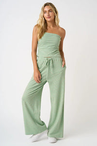Woman wearing mint green striped tube top and wide-leg drawstring pants set from Glitz Fine Clothing
