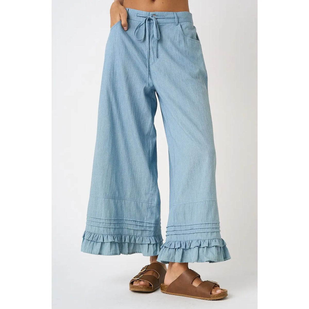Woman wearing Luanne chambray wide-leg pants with a ruffle hem and drawstring waist