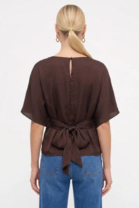 Back view of the Louise Back Tie Dolman Sleeve Silky Blouse in brown, featuring a silky satin finish, an adjustable back tie at the waist, and a keyhole button closure at the nape.