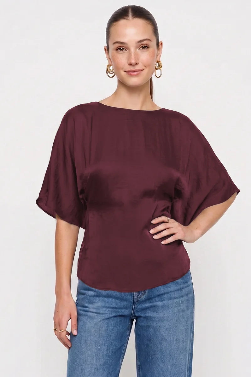 Woman wearing the Louise silky dolman sleeve back tie blouse in burgundy at Glitz Fine Clothing