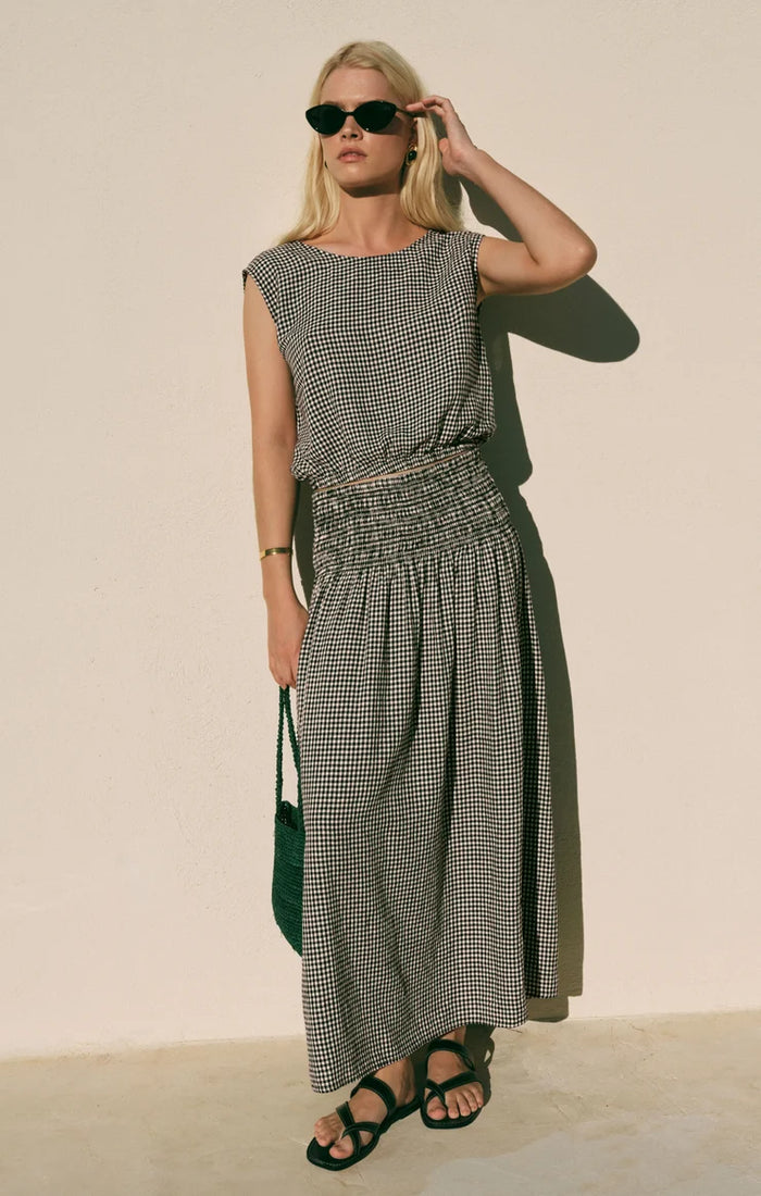 A person wearing a sleeveless black and white gingham top and a matching Brooke Gingham Skirt, which features a high-rise fit and a shirred waistband.