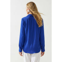 Back view of a person wearing a Naked Zebra - Neck Shirt With Open Seam Sleeve: Black / L in blue with open-seam sleeves and white trousers.