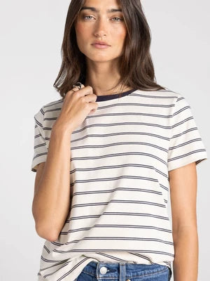 Woman wearing the cream Asher Tee featuring thin navy blue horizontal stripes and a solid navy crew neckline.