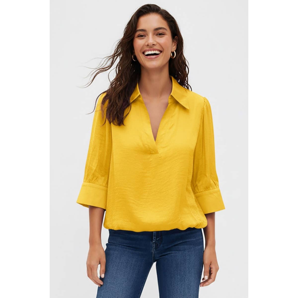 A smiling woman wears a yellow Naked Zebra - Half Sleeve Hi-lo Bubble Hem Blouse with a collar and V-neck, paired with blue jeans.