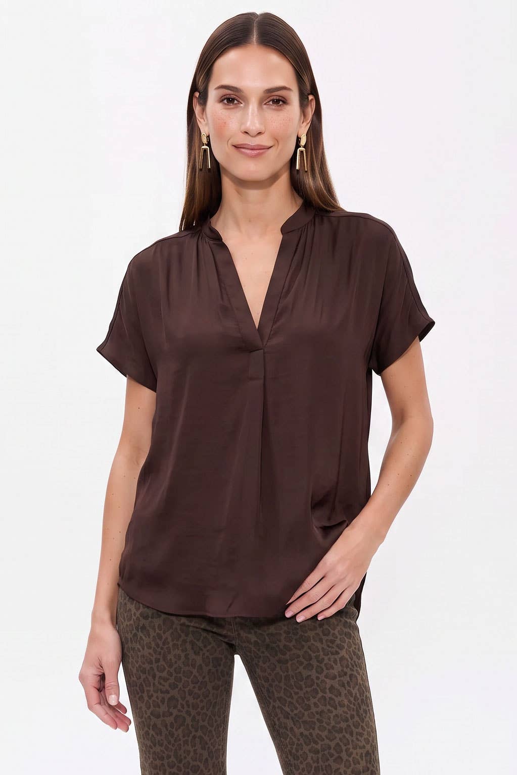 A woman wearing a Naked Zebra - Drop Shoulder Regular Blouse: Chocolate / L, a chocolate brown, short-sleeved drop shoulder blouse with a V-neckline.
