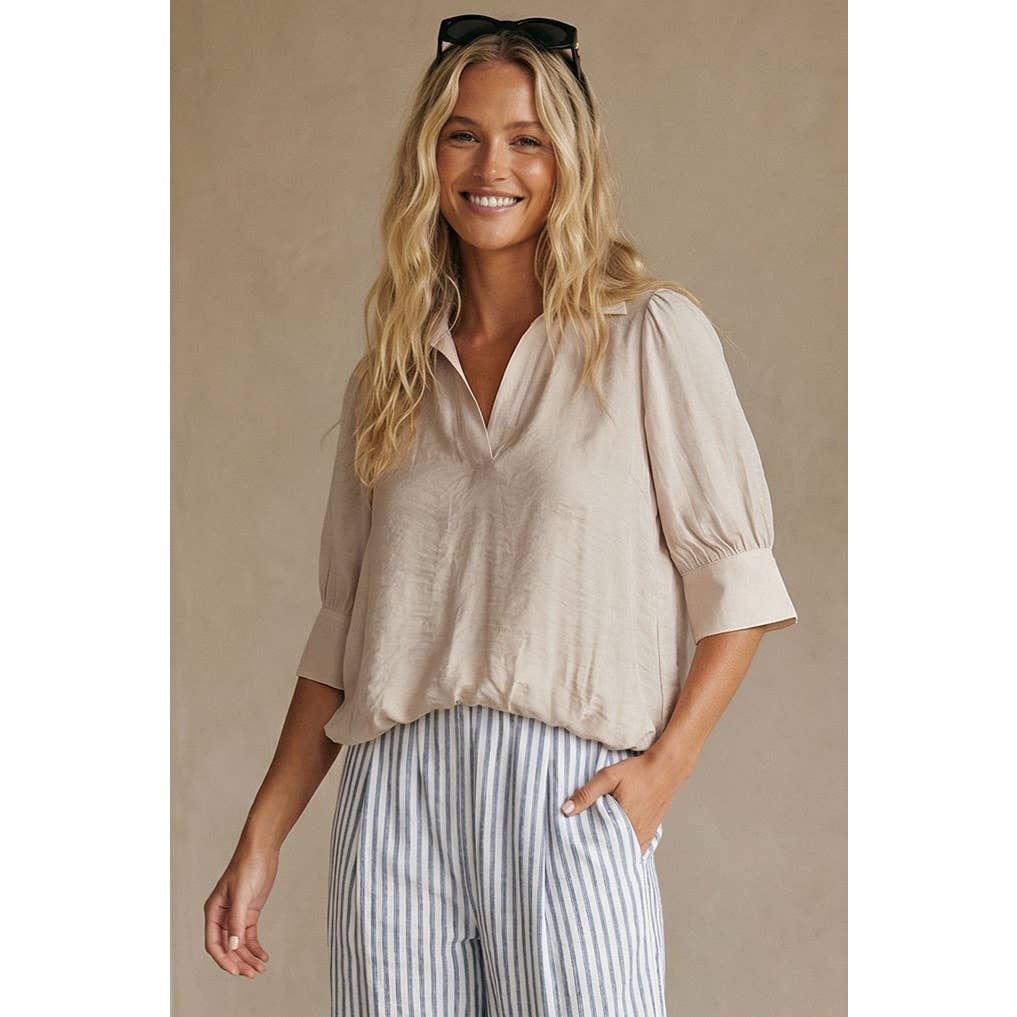 A smiling woman wearing a Naked Zebra - Half Sleeve Hi-lo Bubble Hem Blouse: Wine / L paired with blue and white striped trousers.